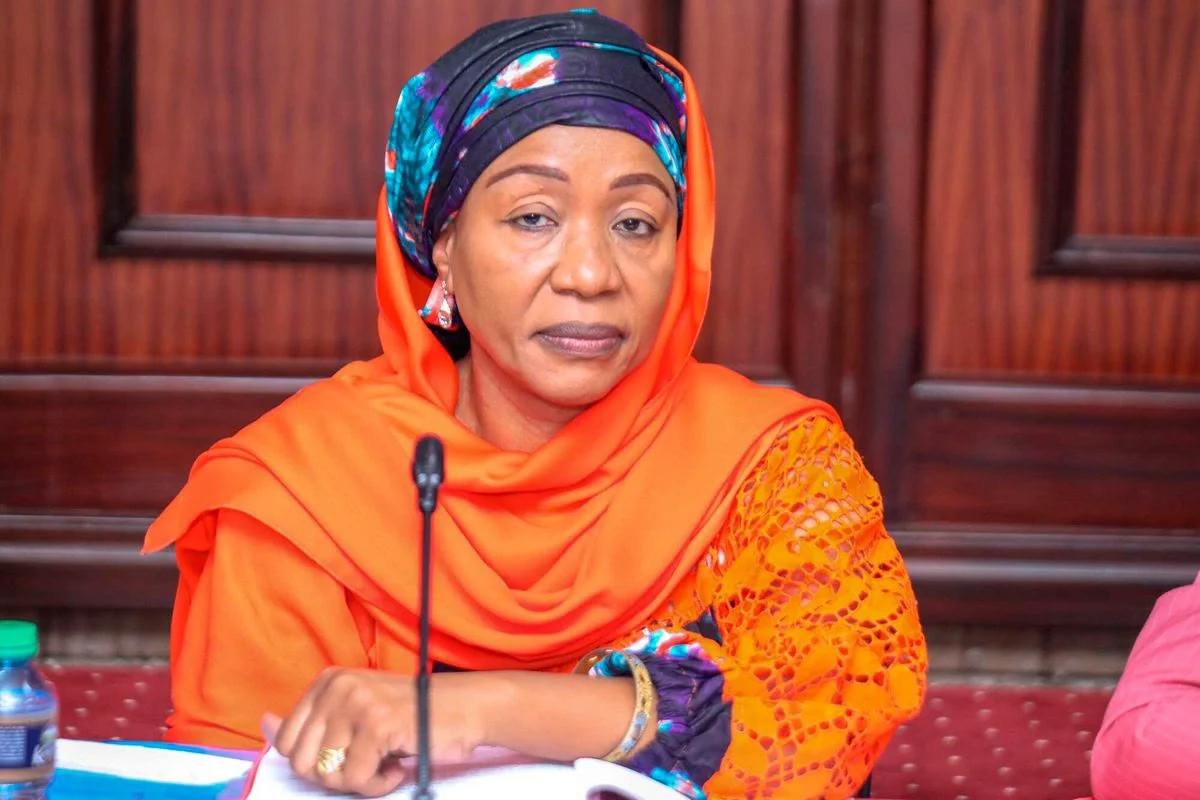 Hamida Kibwana seated at a microphone in an orange outfit, in a client-supplied photograph